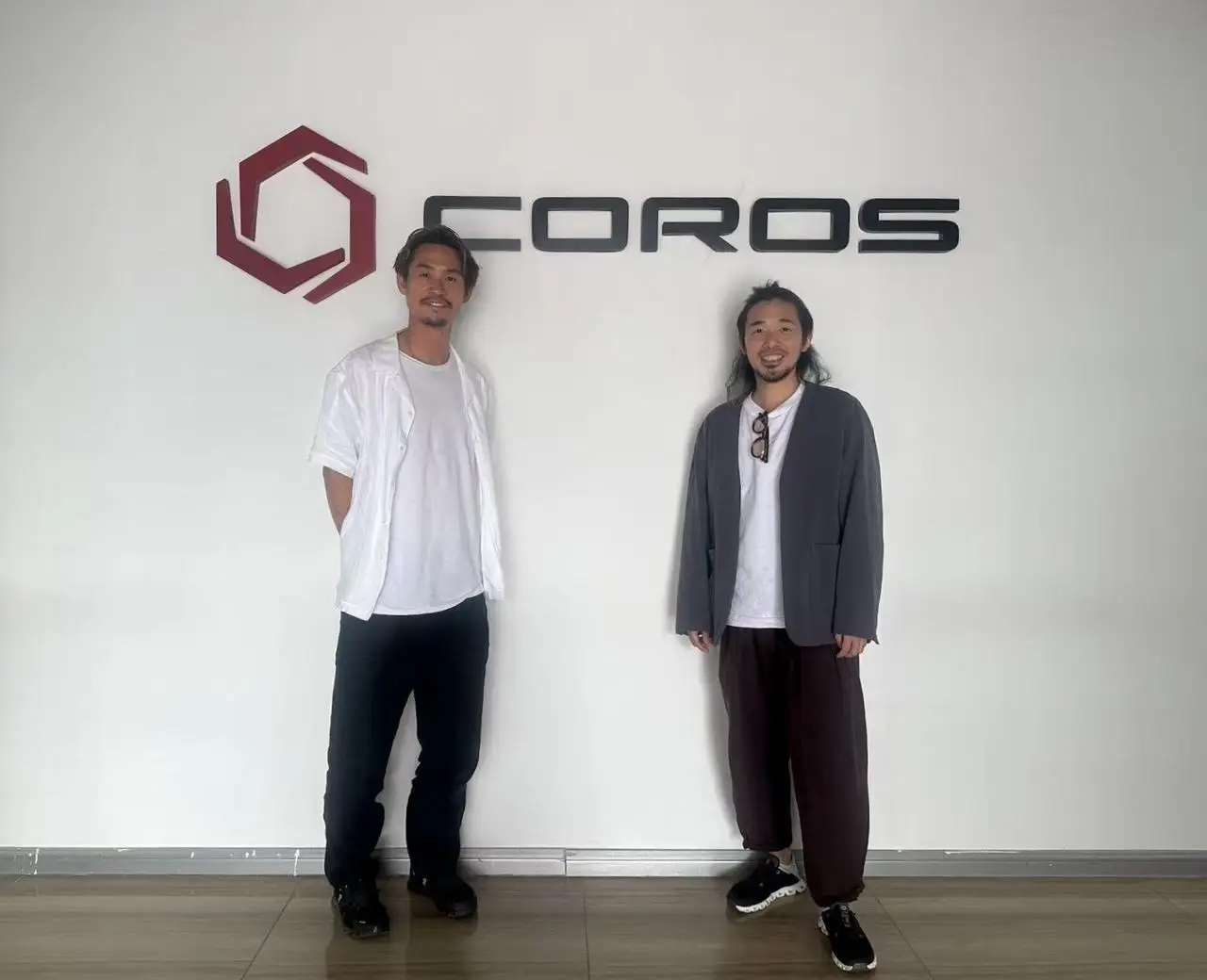 COROSのロゴの前で立つ二人の男性